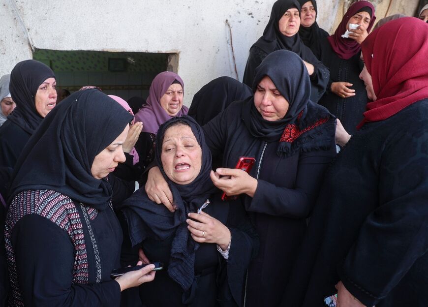 Mourners comfort the mother of Palestinian man Yahya Adwan during his funeral in the village of Azzun in the occupied West Bank, on April 30, 2022, after the Palestinian Health Ministry said a man was shot and killed during an Israeli army operation