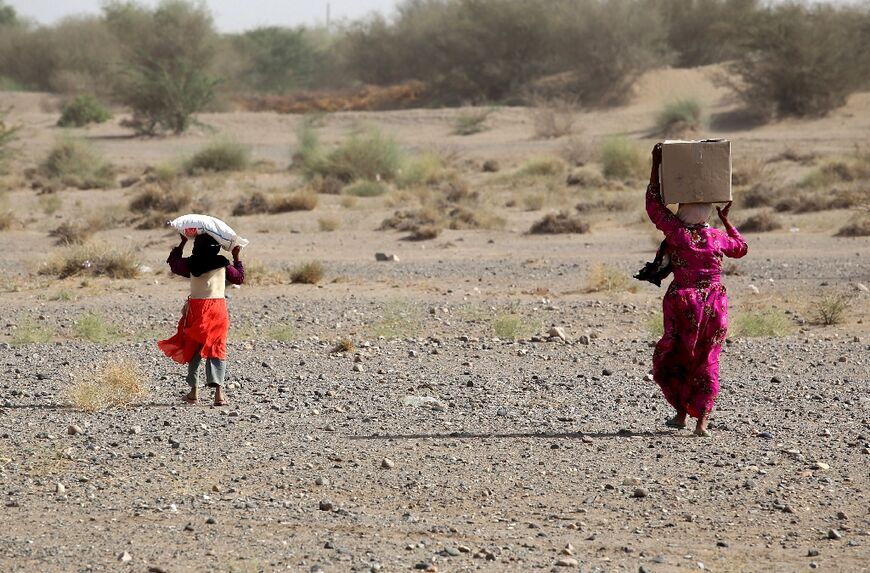 Yemenis displaced by conflict receive food aid and provisions to meet their basic needs at a camp in the Khokha district of Yemen's war-ravaged western province of Hodeida, on January 31, 2022