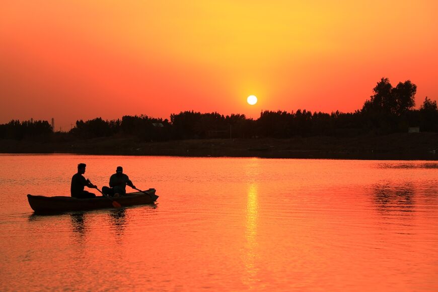 The garbage flows downriver, clogging riverbanks, wetlands and threatening wildlife -- here men row a canoe on the Tigris in Iraq's southern city of Nasiriyah 