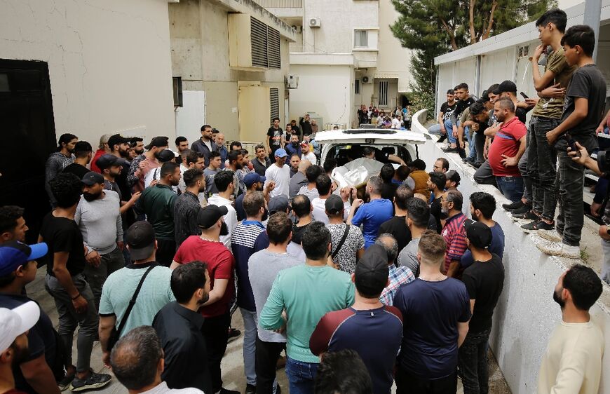 People gather at the entrance of a Tripoli morgue after a migrant boat with nearly 60 people on board capsized off Lebanon's northern shores