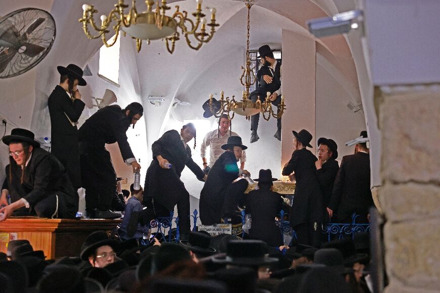 Ultra-Orthodox Jews climb over a fence to reach the tomb of Rabbi Shimon Bar Yochai, a year after 45 people were crushed to death at the Mount Meron site