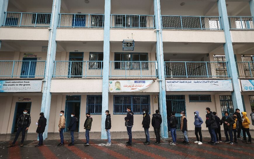 In this file photo taken on January 24, 2022, Palestinian students wait to receive a dose of coronavirus vaccine at an UNRWA school in the Gaza Strip's Al-Shati refugee camp