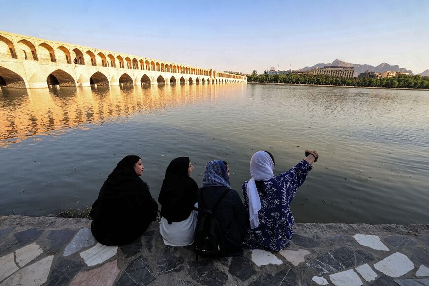 Women pose for a selfie along the bank of the Zayandeh Rood in Iran's central city of Isfahan on May 15, 2022 