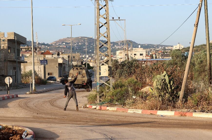 A Palestinian man hurls rocks at an Israeli security forces vehicle following the demolition of Jaradat's home in the village of Silat al-Harithiya, near the flashpoint town of Jenin in the occupied West Bank