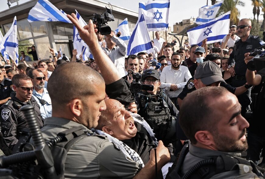 Israeli guards carry a man wearing a Palestinian scarf during the Israeli 'flags march'