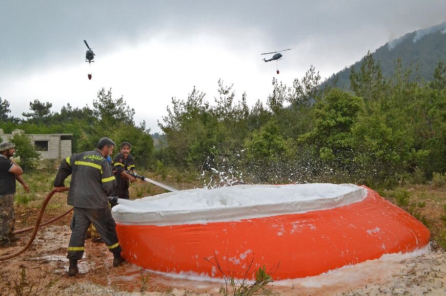 Firefighters ready water to be collected by helicopters tackling a forest blaze