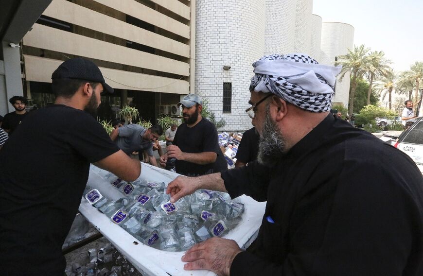 Supporters of Iraqi cleric Moqtada Sadr distribute water to fellow demonstrators, outside Iraq's parliament building on the second day of their occupation 