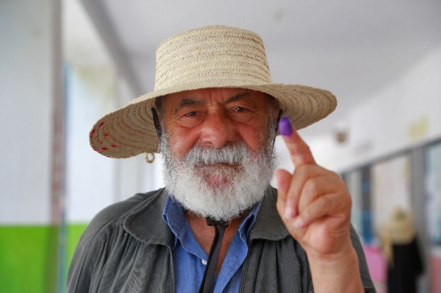 A Tunisian shows that he has voted in a referendum on a draft constitution, at a polling station near Tunis on July 25, 2022