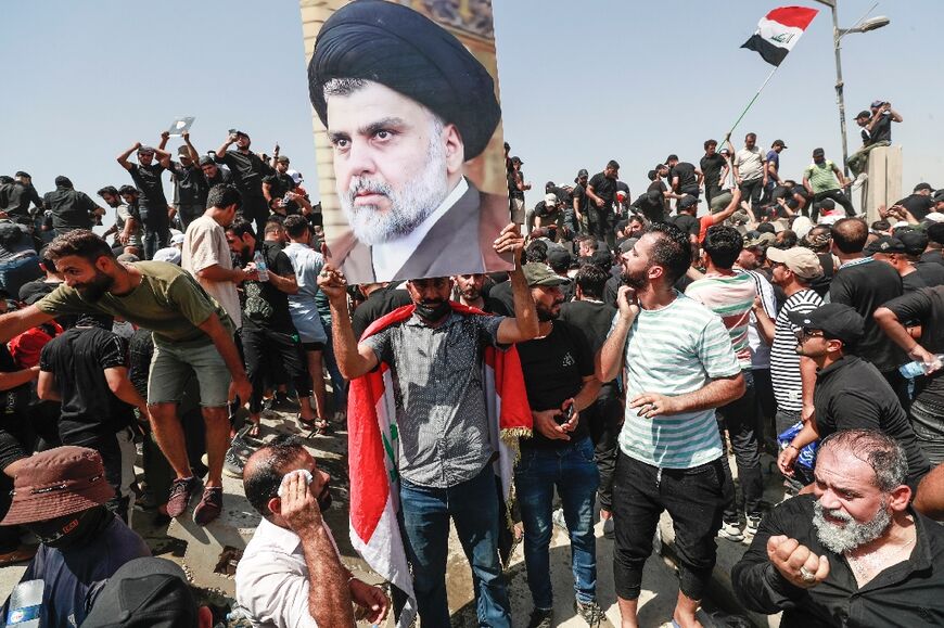 Supporters of the Iraqi cleric Moqtada Sadr raise a portrait of their leader, as they protest at a rival bloc's nomination for prime minister