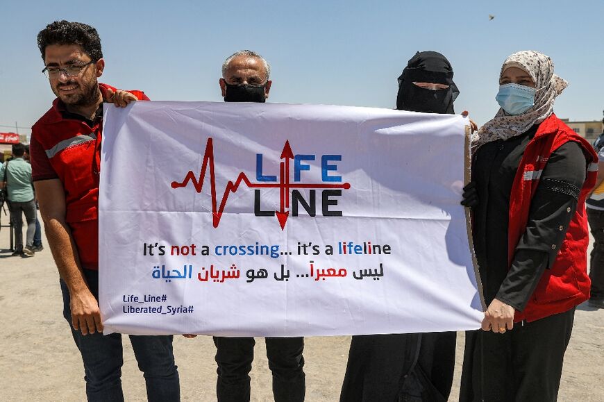 Humanitarian aid workers gather near the town of Sarmada in the rebel-held part of Syria's northwestern Idlib province on July 7, 2022, to demonstrate against the possible closure of the Bab al-Hawa border crossing with Turkey to humanitarian aid