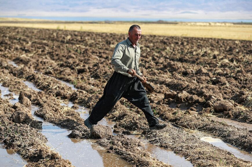 A Kurdish farmer digs with a shovel irrigation ditches for water supplied from a well, in the Rania district near the Dukan Dam 