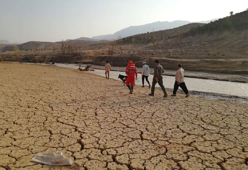 This handout photo made available by the Iranian Red Crescent Society on July 23, 2022 shows rescue workers searching near a river bank after deadly flooding in Estahban county in southern Iran