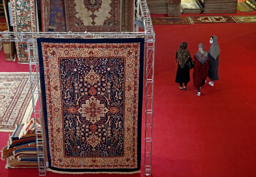 Visitors pass a traditional Iranian carpet design at the 29th Handmade Carpet Exhibition in Tehran 