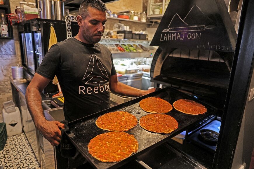 A cook holds a tray of vegan lahmajoon