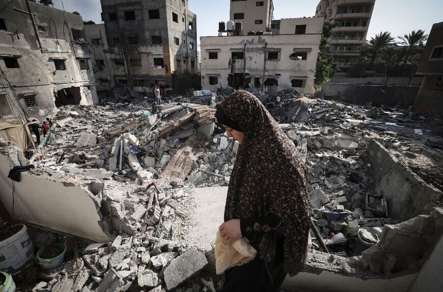 A Palestinian woman walks through rubble in front of her home in Gaza City early on August 8, 2022, following a ceasefire between Israel and Palestinian militants