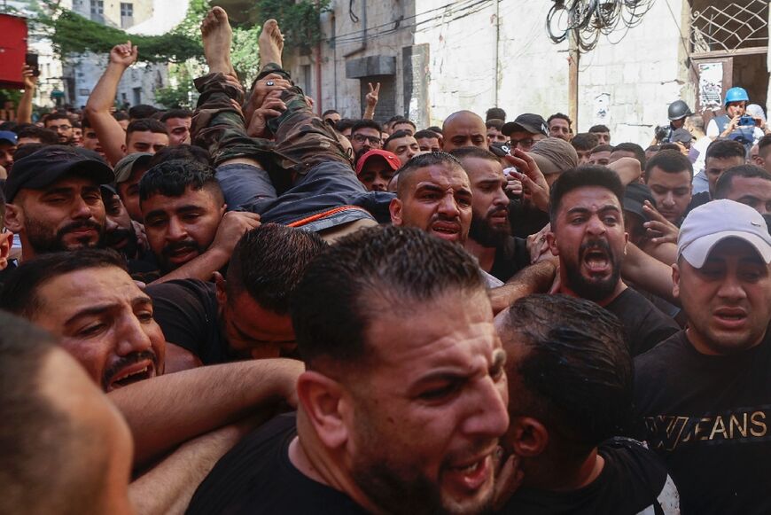 Palestinians evacuate a wounded gunman following clashes with the Israeli army during a raid in the West Bank city of Nablus