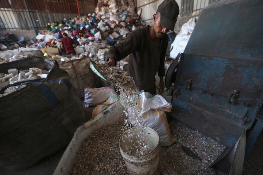 A Palestinian worker prepares plastic for processing: but with the grinder relying on electricity, they are frequently interrupted by Gaza's chronic power cuts