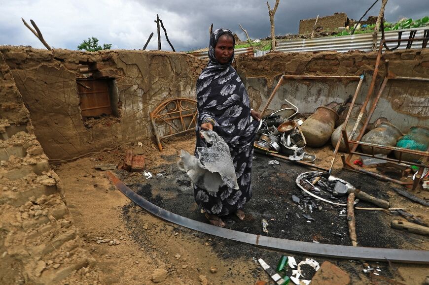 A Sudanese lady stands inside the wreckage of her home torched during clashes in Blue Nile state