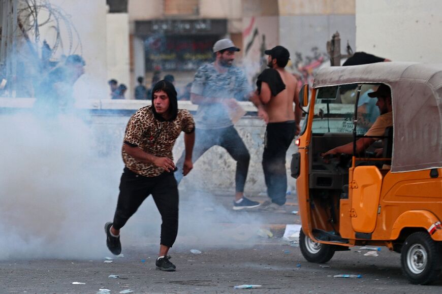 Supporters of Shiite Muslim cleric Moqtada Sadr run for cover from tear gas fired by Iraqi security forces amid clashes in Tahrir Square in the centre of Iraq's capital Baghdad