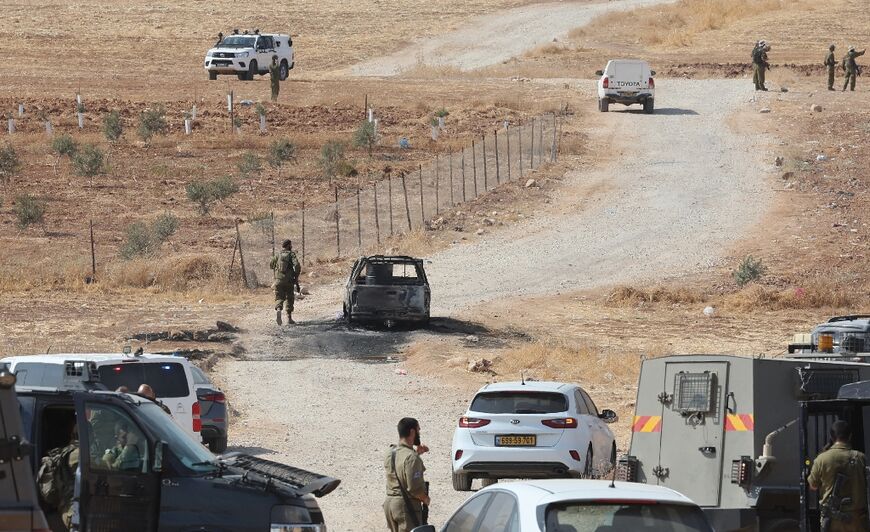 Security forces surround the burnt car the attackers had used