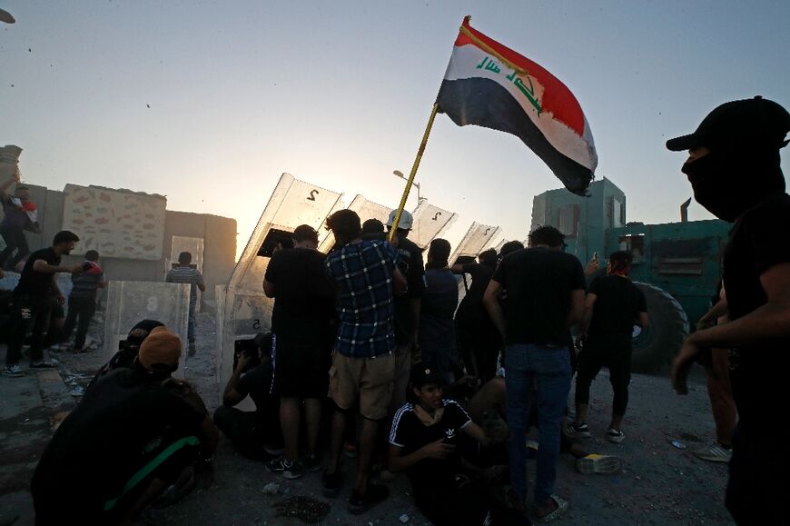 Supporters of Shiite Muslim cleric Moqtada Sadr take cover amid clashes with Iraqi security forces in Tahrir Square in the centre of Iraq's capital Baghdad on September 28, 2022