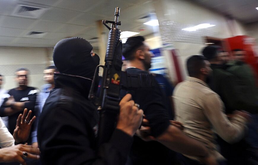 A member of The Lions' Den group escort injured men into a hospital after clashes with Israeli forces in Nablus early Tuesday