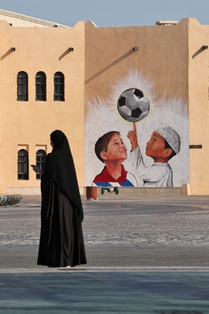 A woman walks past a mural in the Katara Cultural Village, in Qatar's capital Doha, on October 11, 2022 ahead of the FIFA 2022 football World Cup