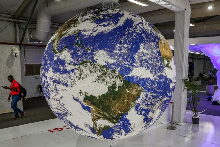 A person walks past an Earth globe in the deserted hall at the Sharm el-Sheikh International Convention Centre near the end of the COP27 climate conference