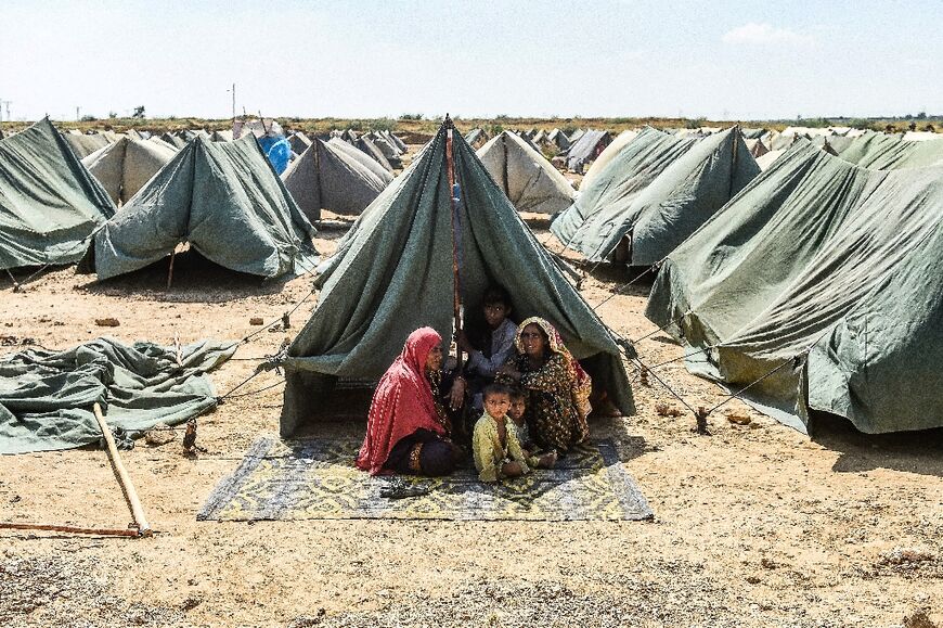 A family in a makeshift shelter in Pakistan's Sindh province after catastrophic floods this year put a third of the country under water and displaced eight million