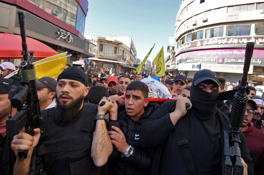 Palestinian mourners and gunmen carry the body of a 16-year-old youth who was killed during clashes with Israeli soldiers in the West Bank city of Nablus the previous day, during his funeral on November 23, 2022