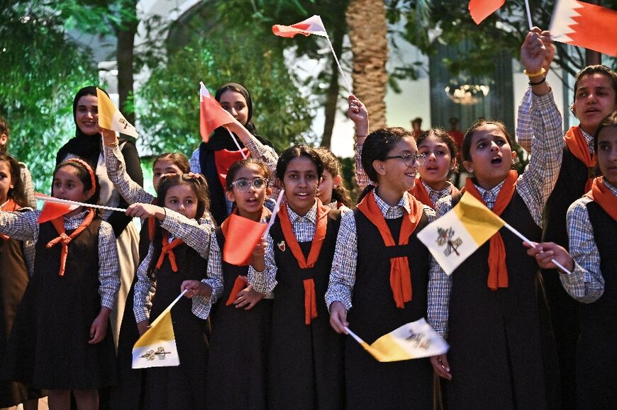 Children wave flags as they welcome the Pope outside the Royal Palace in Awali, south of the Bahraini capital Manama, on November 3, 2022.