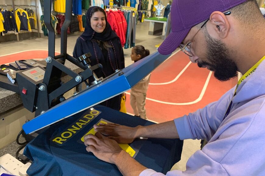 An employee at the Saudi Al Nassr FC shop prepares a t-shirt bearing the name Ronaldo 