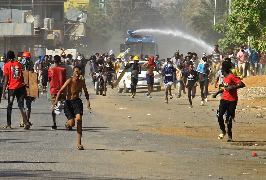 Demonstrators flee from a water cannon during clashes with security forces in Sudan's capital Khartoum on Monday, in rejection of a deal aimed at ending the crisis caused by the 2021 coup