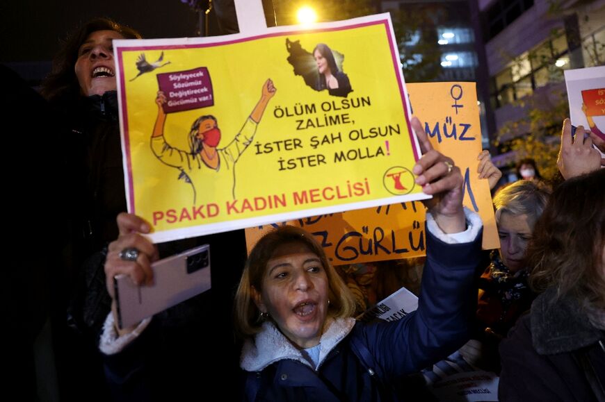 A woman holds a sign which reads "Death to the tyrants" with an Iranian map and a portrait of Mahsa Amini, during a demonstration in Ankara, on November 25, 2022