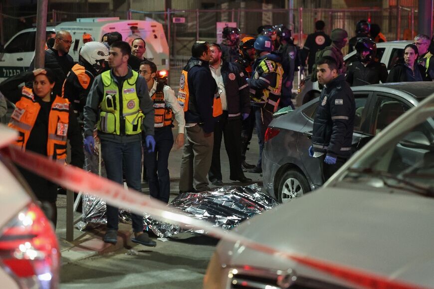 Israeli emergency service personnel and security forces stand near a covered body after the shooting in a settler neighbourhood of Israeli-annexed east Jerusalem