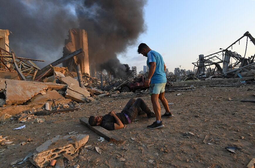 In this file photo taken on August 4, 2020, a wounded man lies on the ground near the scene of the massive explosion that hit Beirut's port 