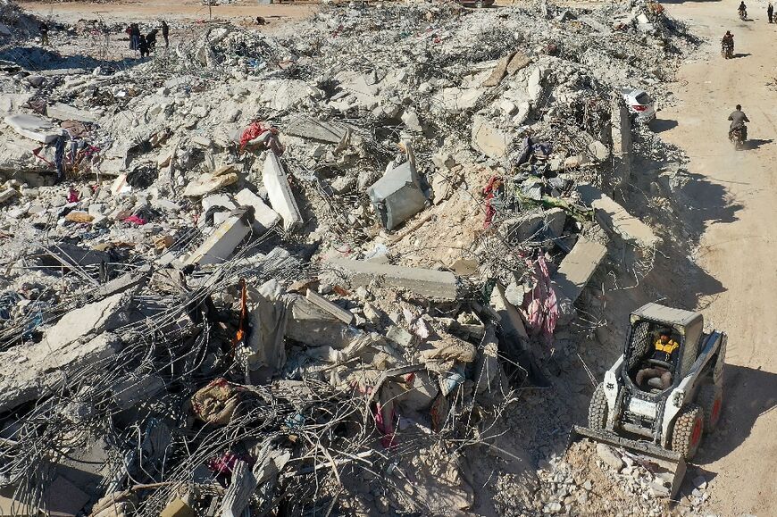 A tractor works to move rubble from a collapsed building in the Syrian rebel-held town of Jindayris 