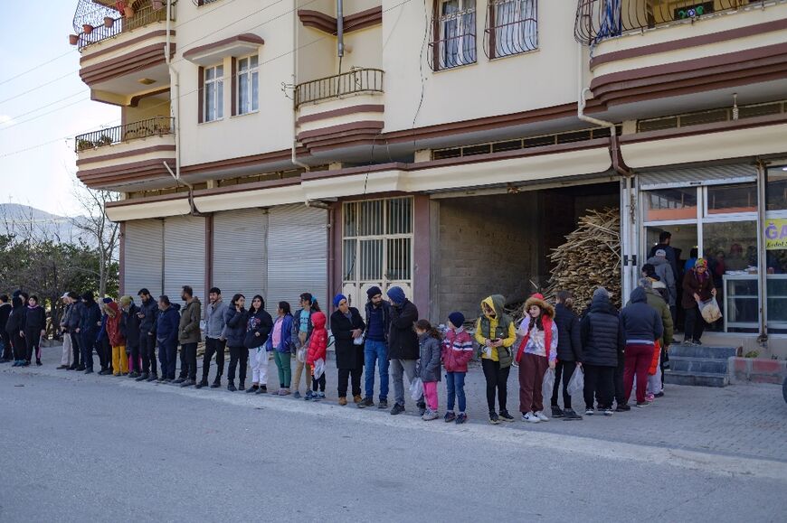 Residents wait in a queue outside a bakery giving out free bread 