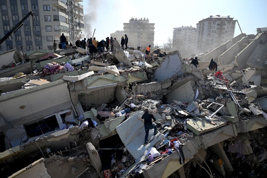 Families stand as rescue officials search the rubble of collapsed buildings in the Turkish city of Kahramanmaras