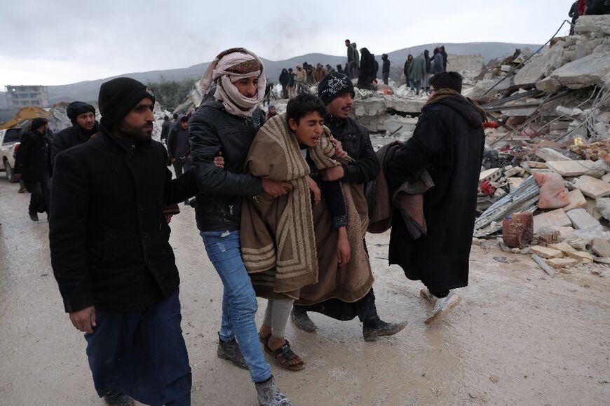 A youth is comforted as residents and rescuers search for victims and survivors in Besnaya village in Syria's rebel-held northwestern Idlib province