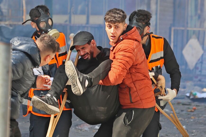 Palestinians carry away a wounded man during an Israeli raid in the occupied West Bank city of Nablus on February 22