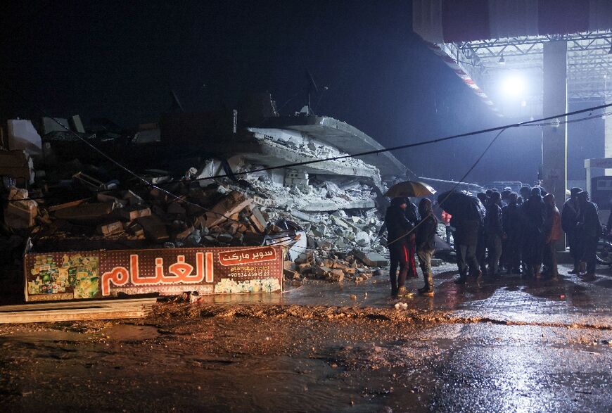 Residents gather in front of the rubble of a collapsed building in Azmarin, a village in Syria's northwestern province of Idlib