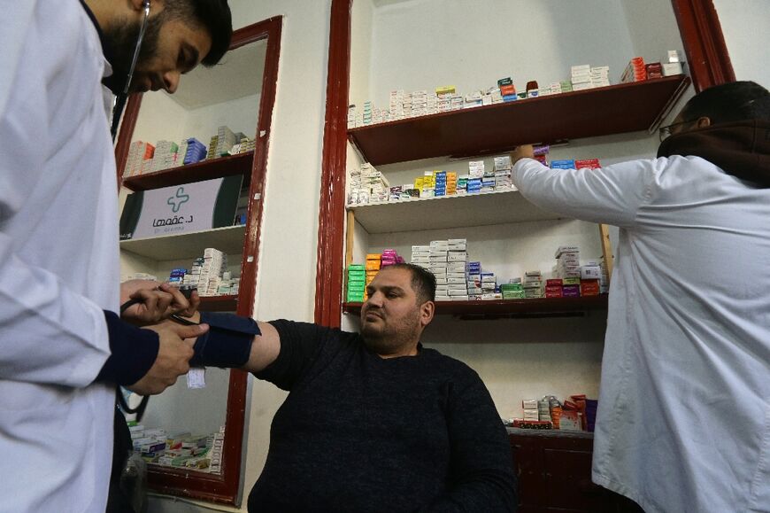 Mohammed Shasho (L) and Jaafar Mustafa test the blood pressure of a patient a medical centre in Damascus