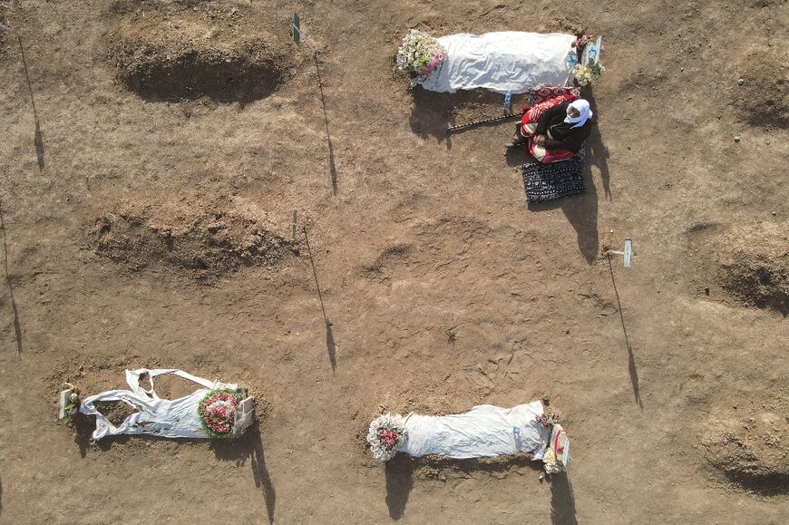 An aerial picture shows a mourner next to a coffin during a mass funeral for Yazidi victims of the Islamic State group