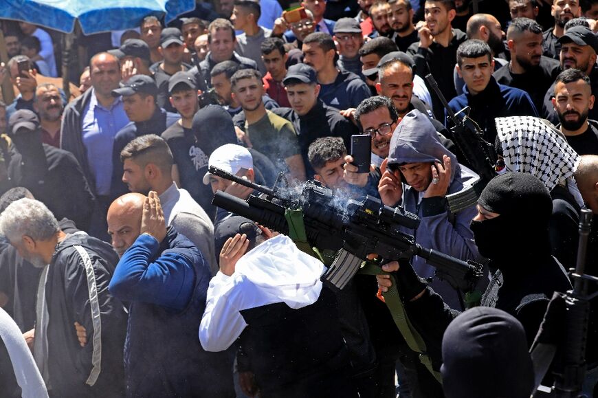 A gunman from the Al-Aqsa Martyrs Brigades fires in the air during the funeral in Nablus of two Palestinians killed in the Israeli army raid