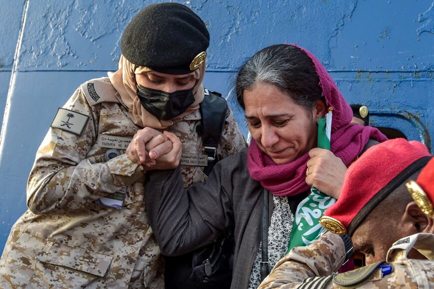 Saudi Navy sailors assist an elderly woman who has been evacuated from Sudan off a ferry passenger ship after arrival at King Faisal navy base in Jeddah on April 26