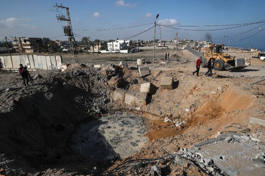 Palestinians inspect the crater left by an Israeli air strike in Deir al-Balah in the central Gaza Strip