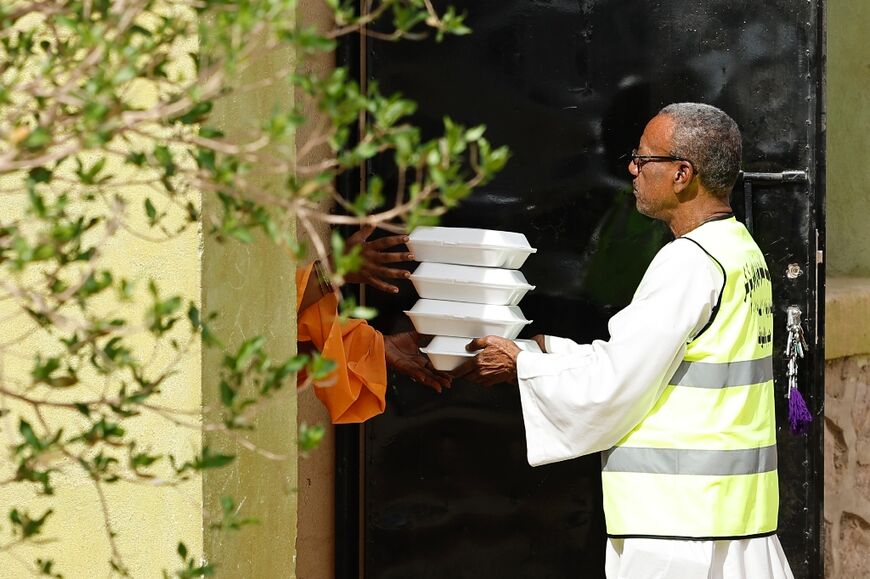 An Egyptian volunteer delivers free meals to a family of Sudanese refugees hosted at an Egyptian home in the village of Wadi Karkar near Aswan 