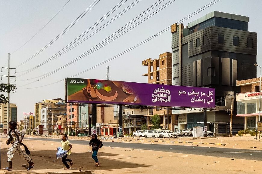 Children run near the burned-out Central Bureau of Statistics office on al-Sittin (Sixty) Street, Khartoum