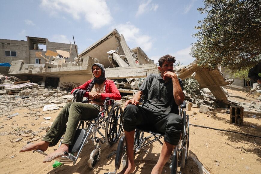 Members of the Palestinian Nabhan family sit in wheelchairs by the rubble of their home, flattened in an Israeli air strike in Beit Lahiya in the northern Gaza Strip